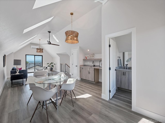 dining space featuring hardwood / wood-style floors, vaulted ceiling with skylight, sink, and ceiling fan