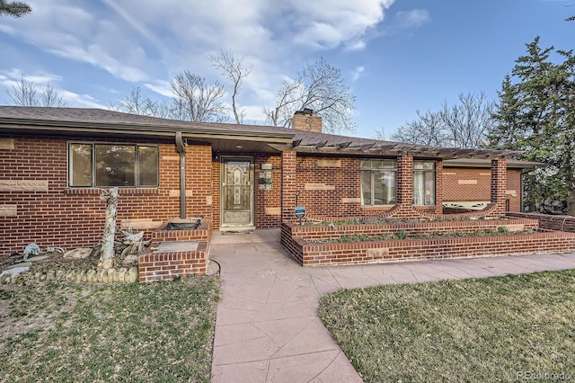 ranch-style home with brick siding and a chimney