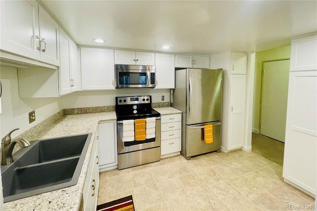 kitchen with white cabinets, sink, light stone countertops, and stainless steel appliances