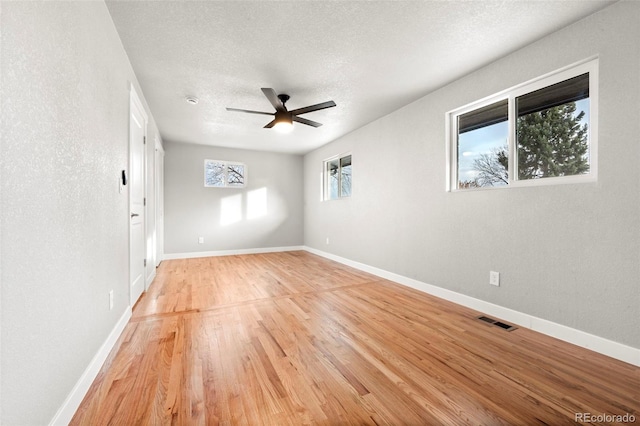 spare room featuring a textured ceiling, light wood-type flooring, and ceiling fan