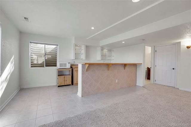 kitchen with kitchen peninsula, light tile patterned floors, and a breakfast bar area