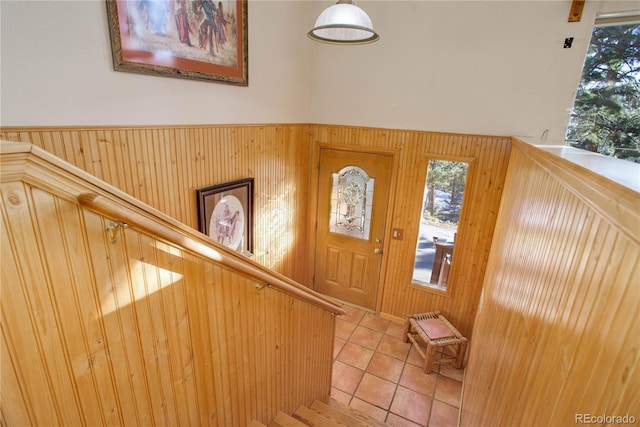 foyer entrance with light tile patterned flooring and wooden walls