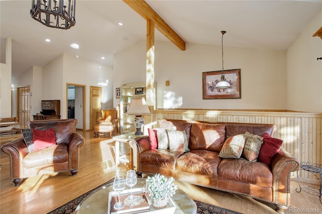 living room featuring beamed ceiling, an inviting chandelier, high vaulted ceiling, and light hardwood / wood-style flooring