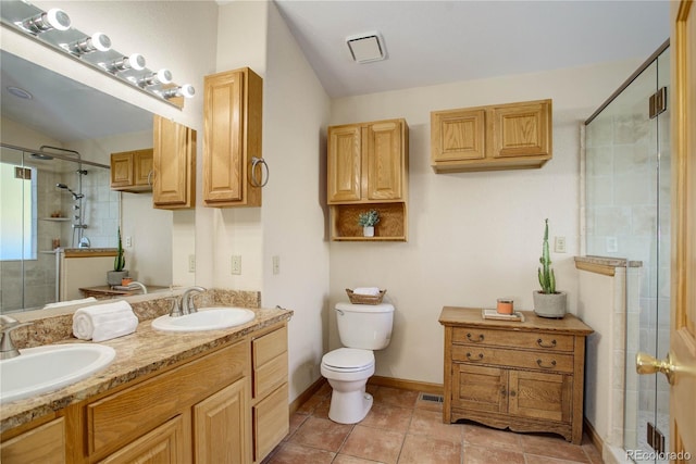 bathroom with vanity, a shower with door, tile patterned floors, vaulted ceiling, and toilet