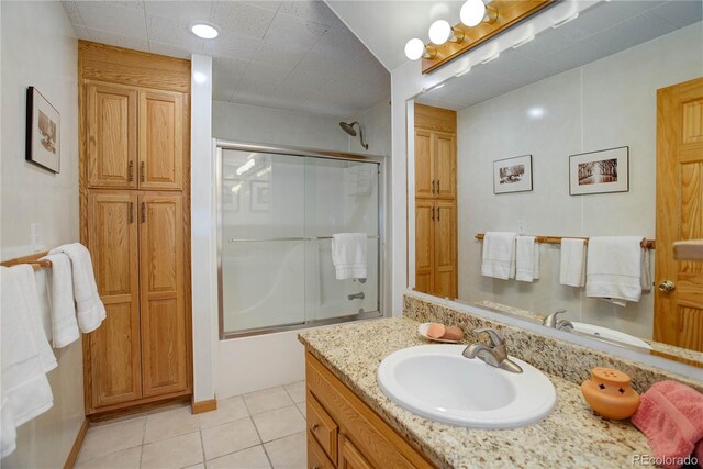 bathroom featuring tile patterned flooring, vanity, and combined bath / shower with glass door