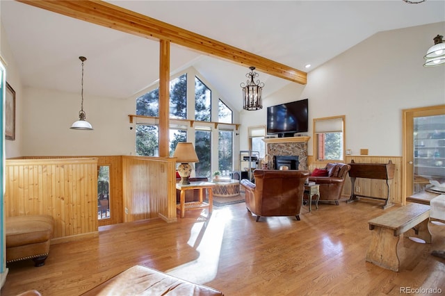 living room with high vaulted ceiling, a stone fireplace, light wood-type flooring, a notable chandelier, and beam ceiling