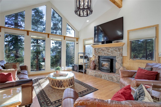 living room featuring hardwood / wood-style flooring, an inviting chandelier, high vaulted ceiling, beamed ceiling, and a wood stove