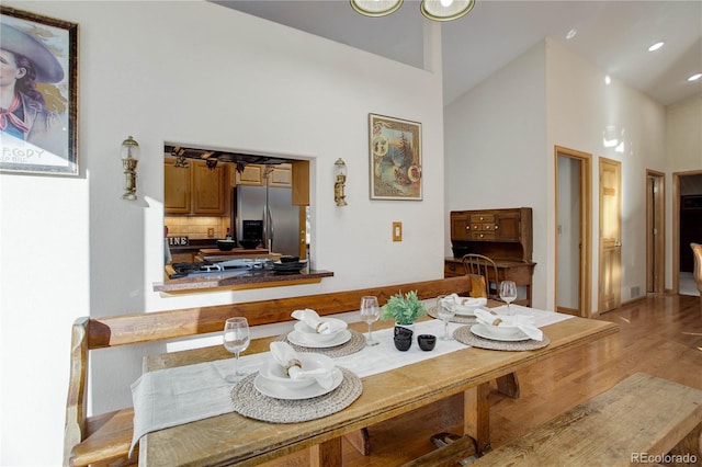 dining area featuring high vaulted ceiling and light hardwood / wood-style floors