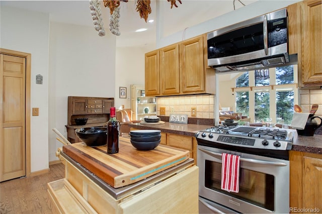 kitchen featuring butcher block counters, light brown cabinets, light hardwood / wood-style flooring, decorative backsplash, and appliances with stainless steel finishes