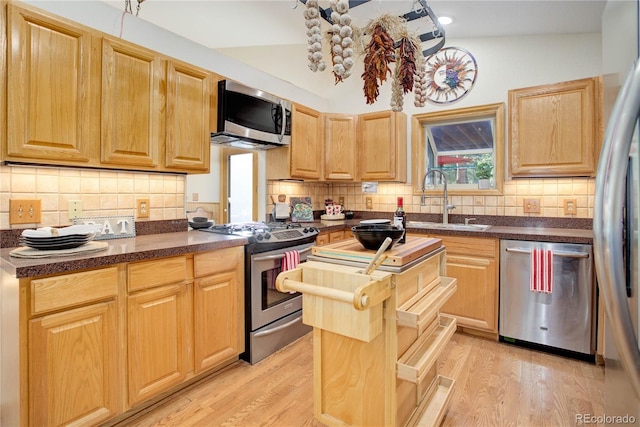 kitchen featuring decorative backsplash, stainless steel appliances, sink, light hardwood / wood-style floors, and lofted ceiling