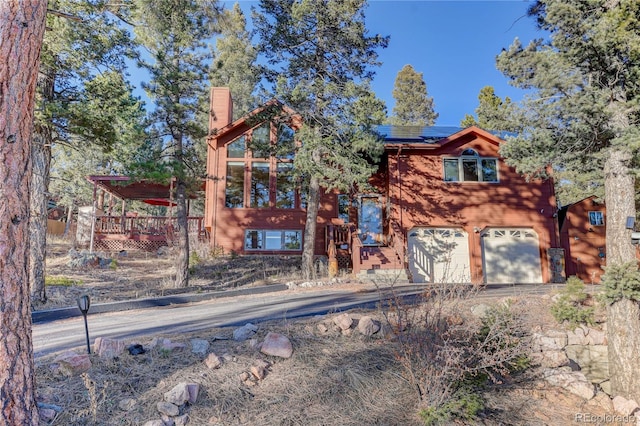 view of front of home with a garage, a deck, and solar panels