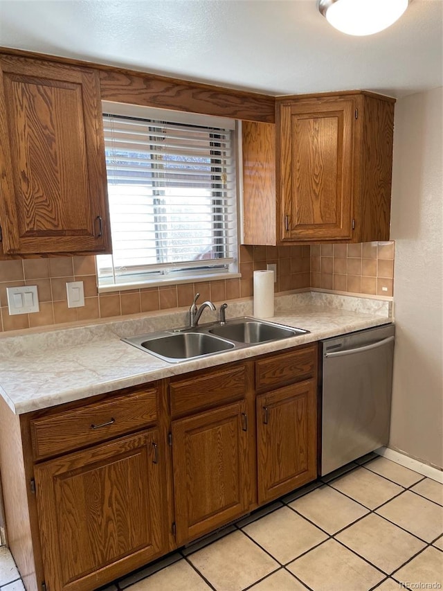 kitchen with light tile patterned flooring, stainless steel dishwasher, sink, and backsplash