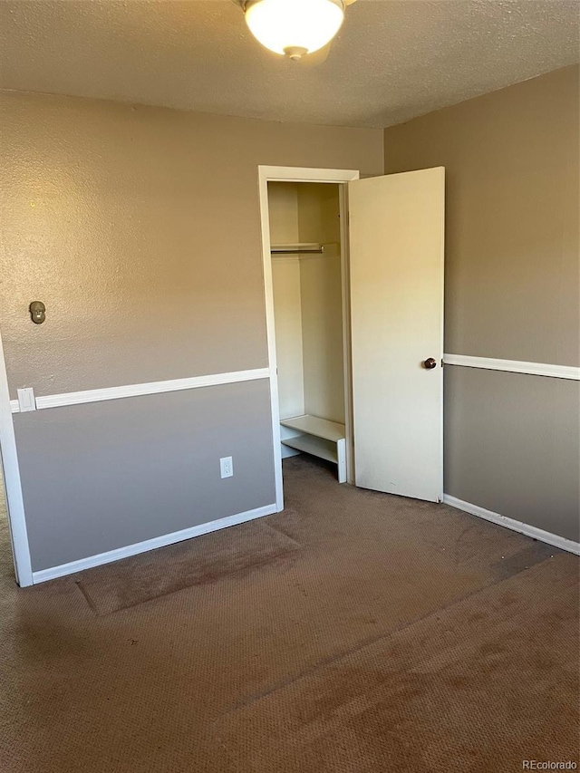 unfurnished bedroom with a closet, a textured ceiling, and dark colored carpet