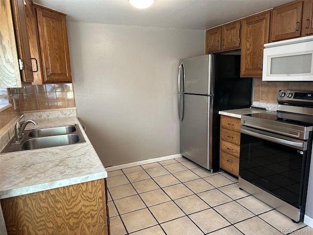 kitchen with appliances with stainless steel finishes, sink, light tile patterned floors, and decorative backsplash