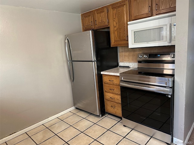 kitchen featuring stainless steel appliances, light tile patterned flooring, and backsplash