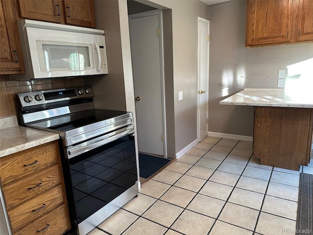 kitchen with tasteful backsplash, stainless steel electric range oven, and light tile patterned floors