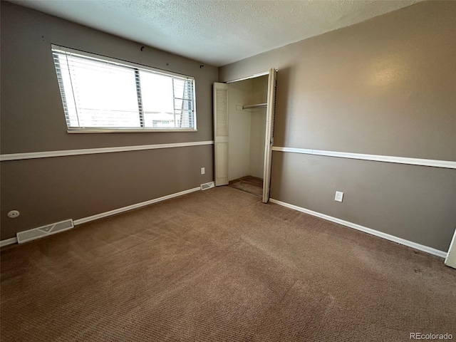 unfurnished bedroom featuring carpet, a textured ceiling, and a closet