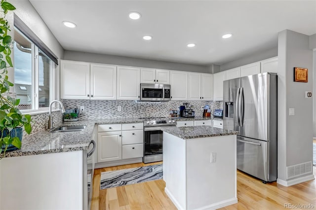 5075 Weeping Willow Cir, Highlands Ranch, CO 80130 - kitchen with stainless steel appliances, light wood-type flooring, light stone countertops, white cabinets, and recessed lighting