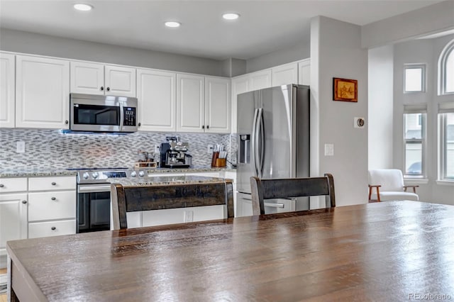 5075 Weeping Willow Cir, Highlands Ranch, CO 80130 - kitchen featuring stainless steel appliances, healthy amount of natural light, white cabinetry, decorative backsplash, and recessed lighting