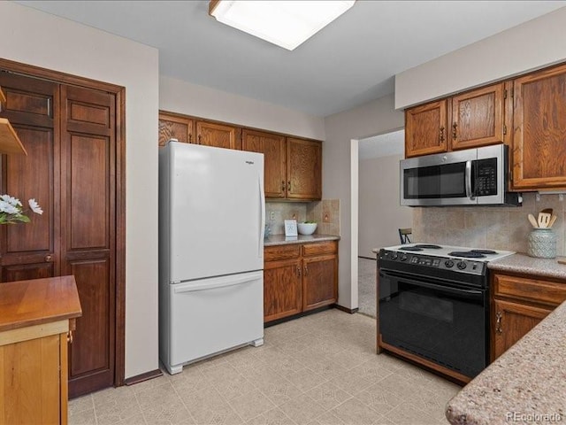 7101 W Yale Ave Unit 1305, Denver, CO 80227 - kitchen with freestanding refrigerator, stainless steel microwave, black / electric stove, light countertops, and backsplash