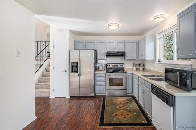 kitchen with appliances with stainless steel finishes, dark hardwood / wood-style floors, sink, and gray cabinetry