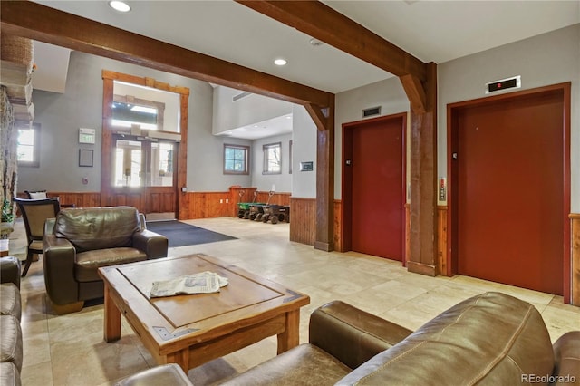 living room featuring beamed ceiling, elevator, and wooden walls