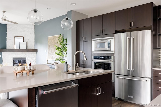 3473 Beeler St, Denver, CO 80238 - kitchen featuring appliances with stainless steel finishes, open floor plan, light countertops, a stone fireplace, and dark brown cabinets