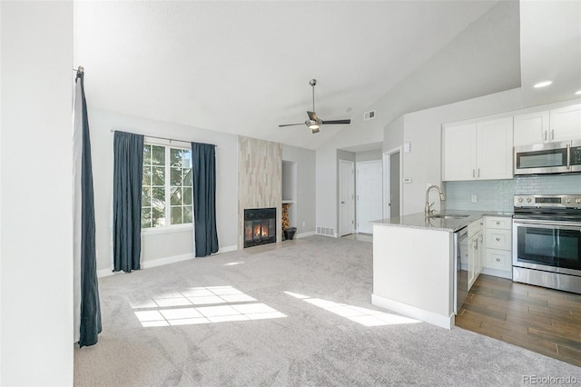 4076 S Carson St Unit H, Aurora, CO 80014 - kitchen with appliances with stainless steel finishes, lofted ceiling, white cabinetry, carpet, and tasteful backsplash