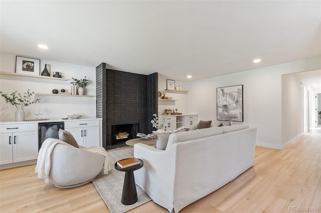 living room featuring a brick fireplace and light hardwood / wood-style flooring