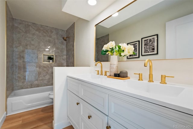 full bathroom featuring hardwood / wood-style flooring, vanity, toilet, and tiled shower / bath