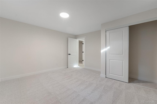 unfurnished bedroom featuring light carpet and a closet