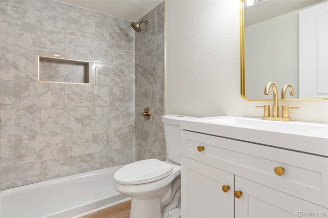 bathroom with vanity, toilet, wood-type flooring, and a tile shower