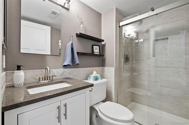 bathroom with toilet, a textured ceiling, tasteful backsplash, a shower with door, and vanity