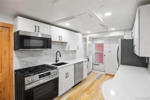 5012 W 36th Ave Unit 5, Denver, CO 80212 - kitchen with stainless steel appliances, a sink, white cabinetry, light wood finished floors, and recessed lighting