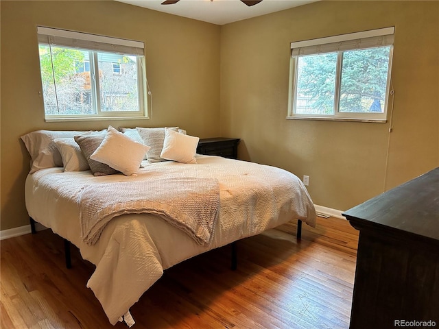 bedroom featuring ceiling fan, light hardwood / wood-style floors, and multiple windows