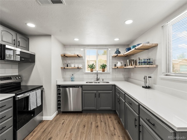 2695 S Logan St, Denver, CO 80210 - kitchen featuring appliances with stainless steel finishes, a sink, gray cabinetry, light wood-style flooring, and a textured ceiling
