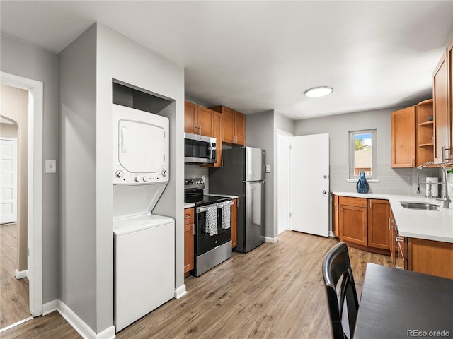 2695 S Logan St, Denver, CO 80210 - kitchen featuring stainless steel appliances, a sink, stacked washer and clothes dryer, open shelves, and decorative backsplash