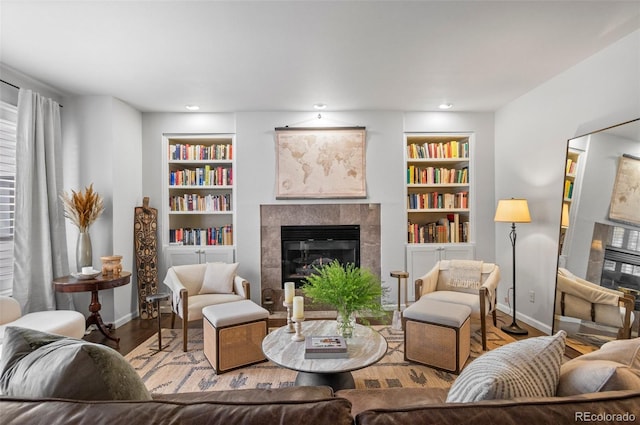 living room featuring a tile fireplace, built in features, and wood-type flooring