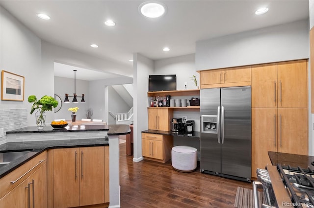 kitchen featuring kitchen peninsula, appliances with stainless steel finishes, dark wood-type flooring, pendant lighting, and dark stone countertops