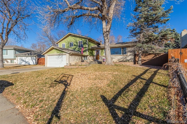 tri-level home featuring concrete driveway, a front yard, roof mounted solar panels, fence, and a garage