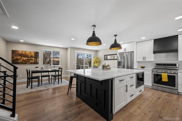 8334 Allison Ct, Arvada, CO 80005 - kitchen featuring appliances with stainless steel finishes, wall chimney range hood, recessed lighting, white cabinets, and light countertops