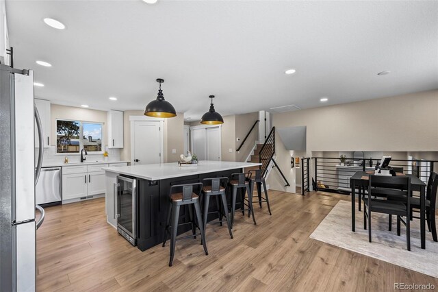 8334 Allison Ct, Arvada, CO 80005 - kitchen with stainless steel appliances, beverage cooler, a kitchen island, white cabinetry, and a sink
