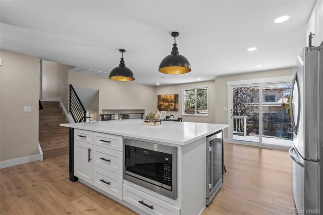 8334 Allison Ct, Arvada, CO 80005 - kitchen with freestanding refrigerator, beverage cooler, built in microwave, white cabinetry, and light wood-style flooring