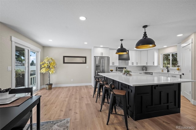 8334 Allison Ct, Arvada, CO 80005 - kitchen featuring stainless steel appliances, white cabinets, light countertops, baseboards, and a large island