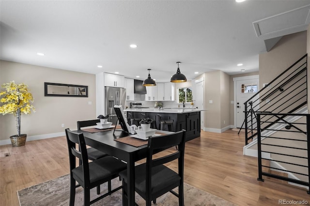 8334 Allison Ct, Arvada, CO 80005 - dining area featuring baseboards, recessed lighting, light wood-style floors, and stairs