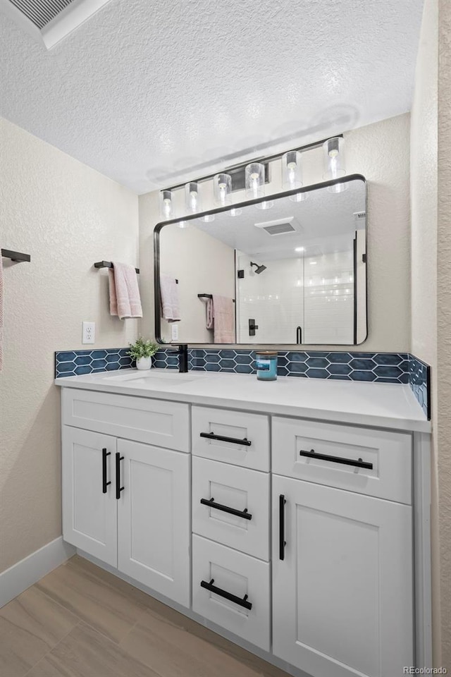 8334 Allison Ct, Arvada, CO 80005 - full bath with a textured ceiling, double vanity, a stall shower, a textured wall, and decorative backsplash