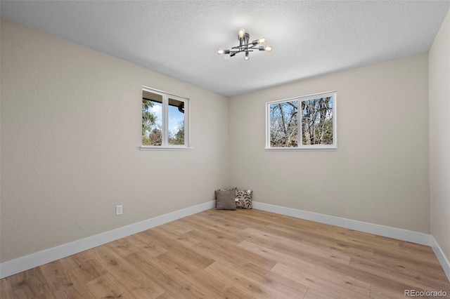 8334 Allison Ct, Arvada, CO 80005 - empty room with plenty of natural light, a chandelier, light wood-style flooring, baseboards, and a textured ceiling
