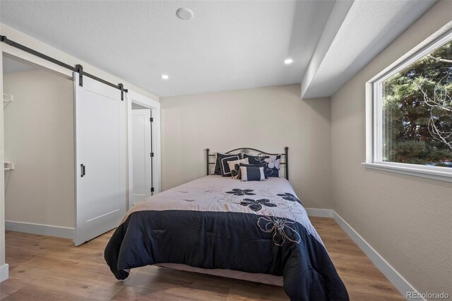 8334 Allison Ct, Arvada, CO 80005 - bedroom with a barn door, light wood finished floors, baseboards, and recessed lighting