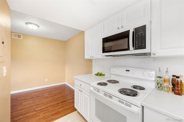 kitchen with white appliances, light wood-type flooring, and white cabinets