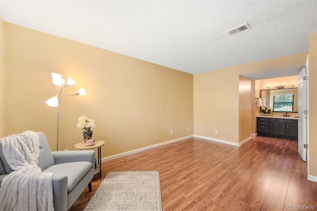 living area with wood-type flooring, sink, and a textured ceiling